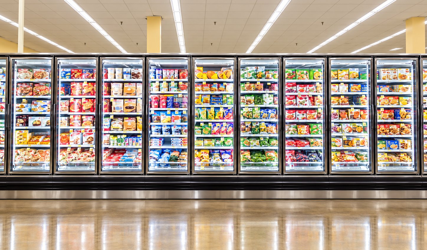 A long row of bright glass-door display freezers in a supermarket