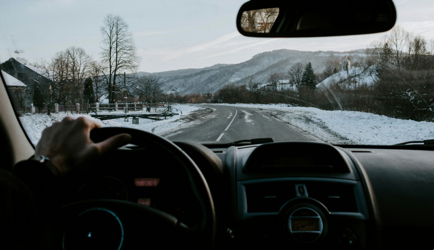 Driver's view through a clear windshield onto a snowy winter road