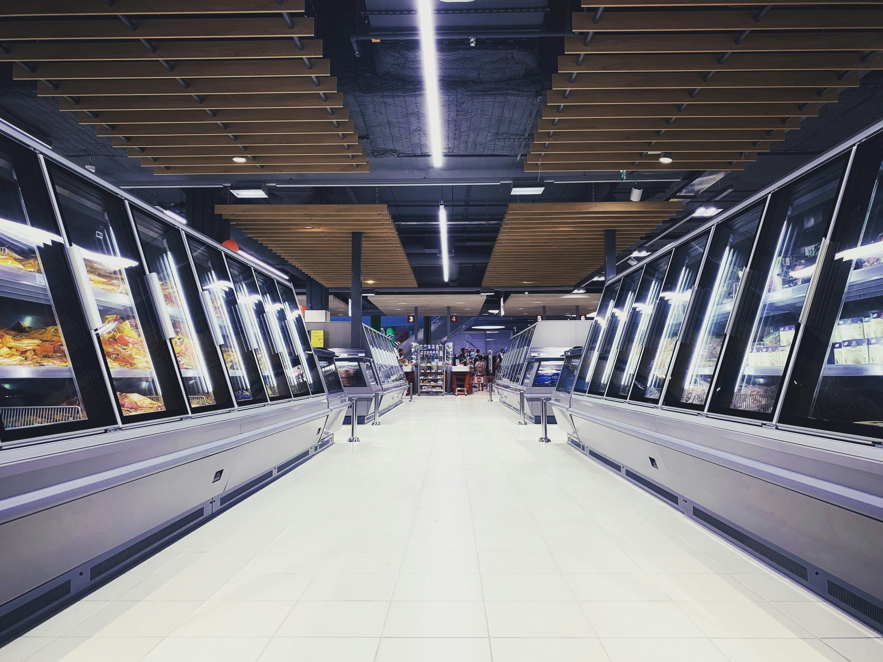 Supermarket aisle lined with glass-door display freezers